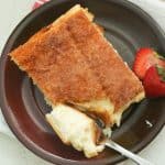 sopapilla cheesecake bar with a strawberry on a plate with a strawberry on the side.