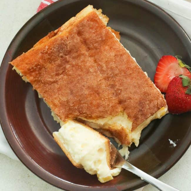 sopapilla cheesecake bar with a strawberry on a plate with a strawberry on the side.