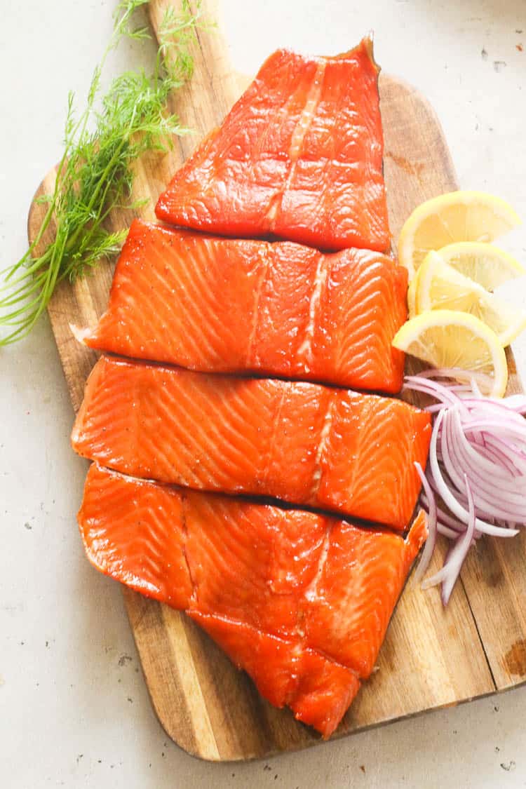 salmon on achopping board with lemon wedges, onion slices, and thyme