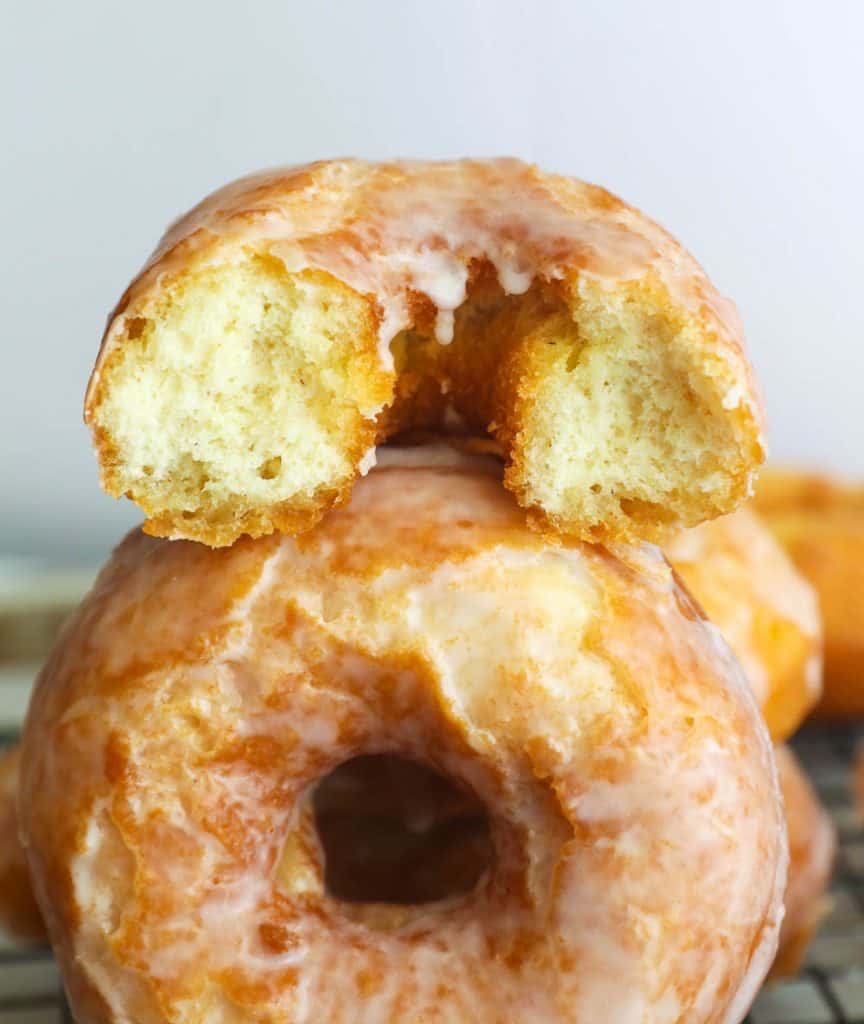 half donut on top of a whole glazed old fashioned doughnut