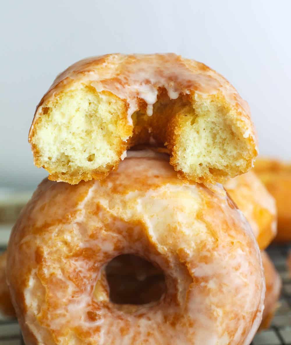 Half donut on top of a whole glazed old fashioned doughnut