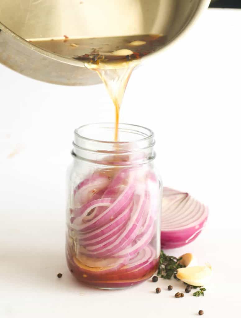 Pouring the vinegar solution in the jar with onions