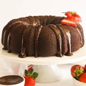 Chocolate Pound Cake on a white cake stand with sliced strawberries on top