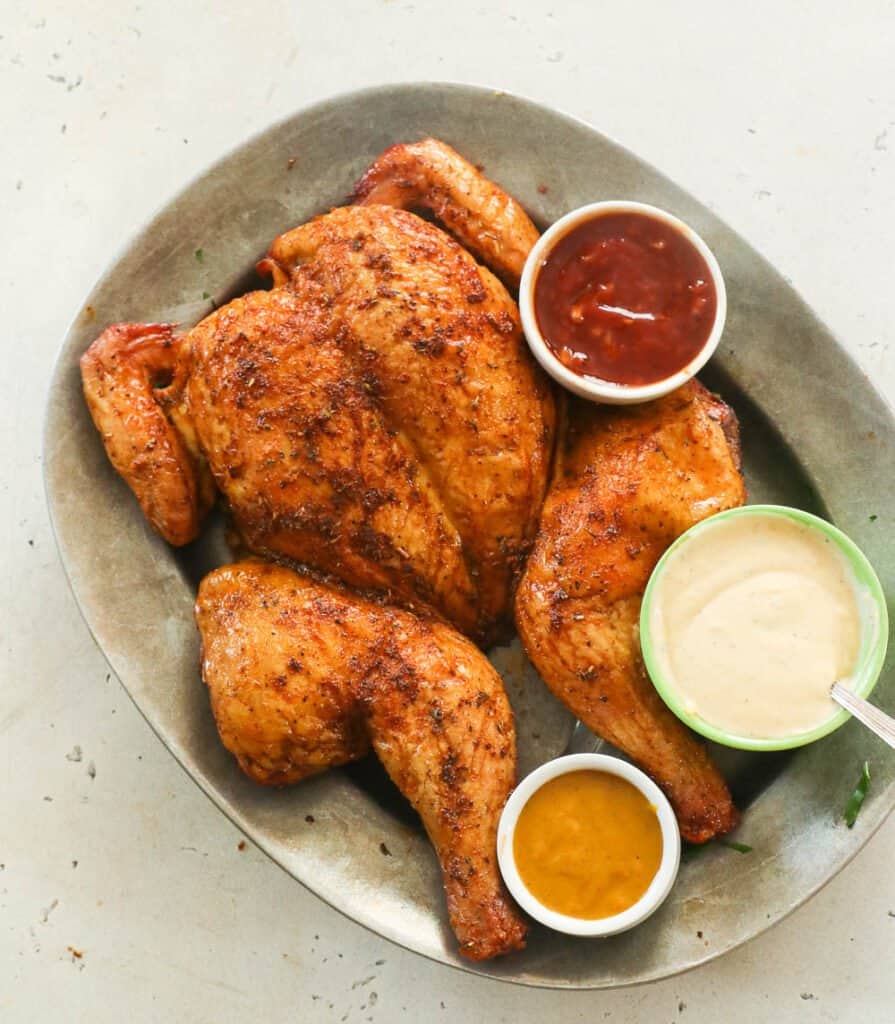 Smoked Spatchcock Chicken with traditional, white, and mustard BBQ sauce