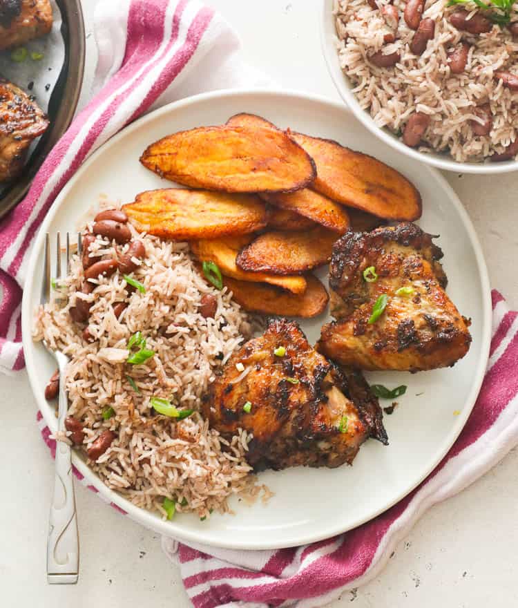 Jamaican rice and beans with chicken and fried plantains on a plate