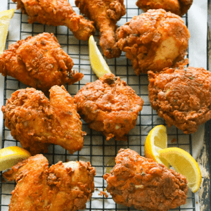 Southern fried chicken with lemon wedges on a rack