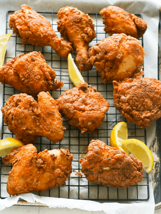 Southern fried chicken with lemon wedges on a rack