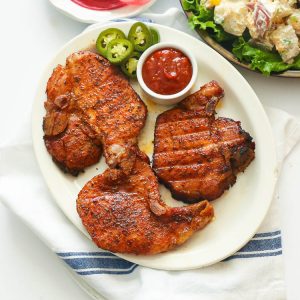 Three pork chops on a white plate