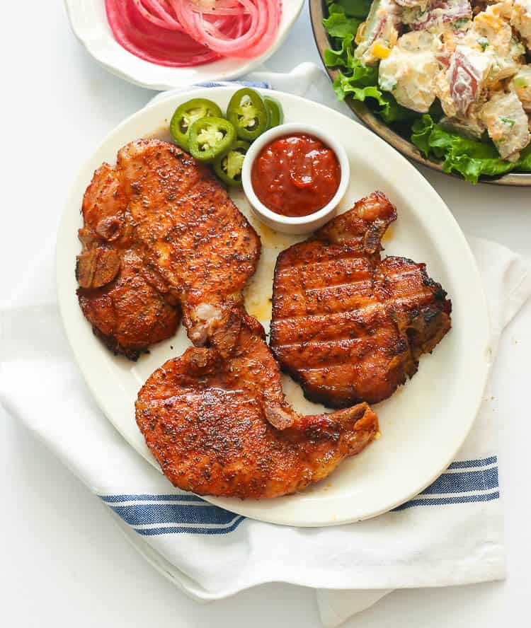 Three pork chops on a white plate