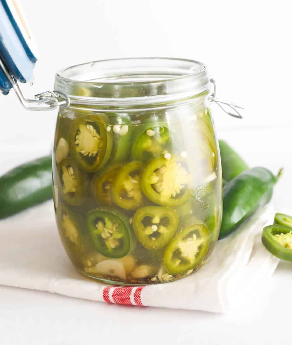 An opened jar full of pickled jalapeno peppers