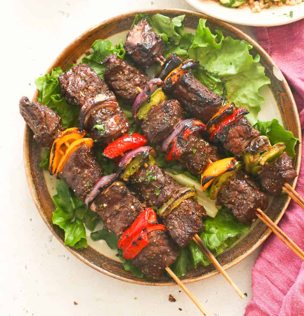 Four steak kabobs on a bed of lettuce