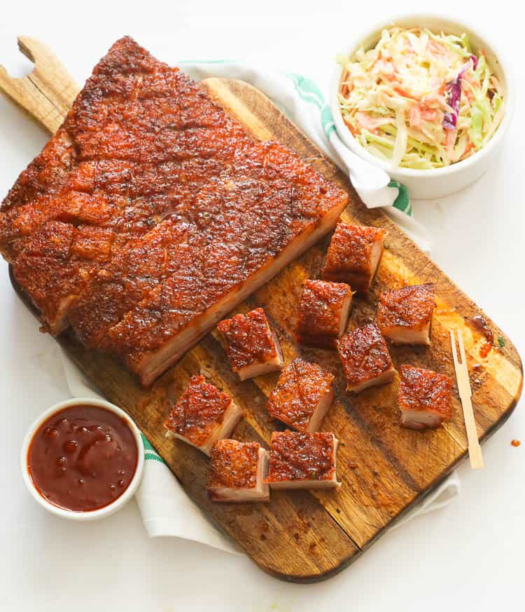 Top view of smoked pork belly on a chopping board with coleslaw