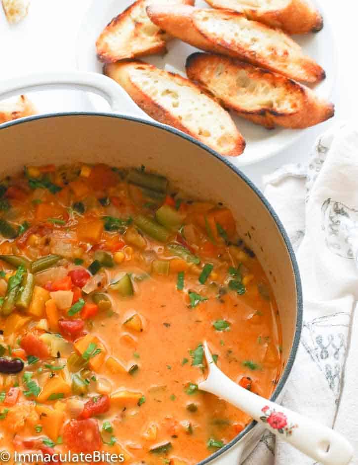 A pot of vegetable soup with garlic bread