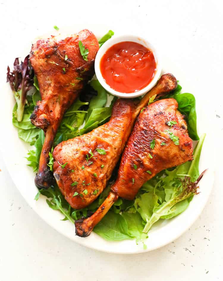 Smoked turkey leg on a bed of veggies with barbecue sauce