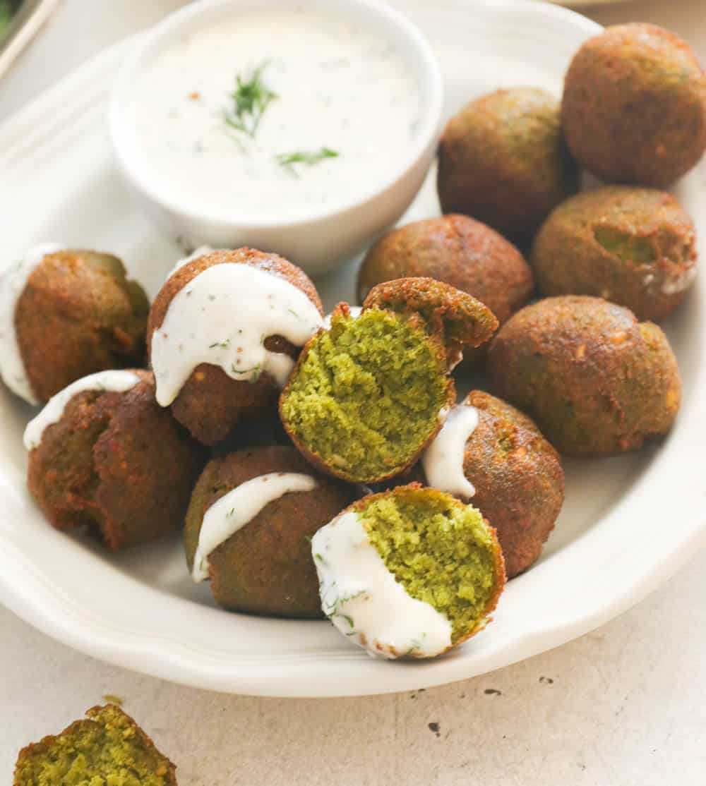 Falafel in a white plate drizzled with sauce