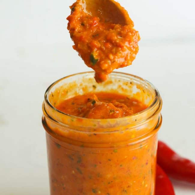 Spooning up beautifully spicy Peri Peri Sauce in a Glass Jar