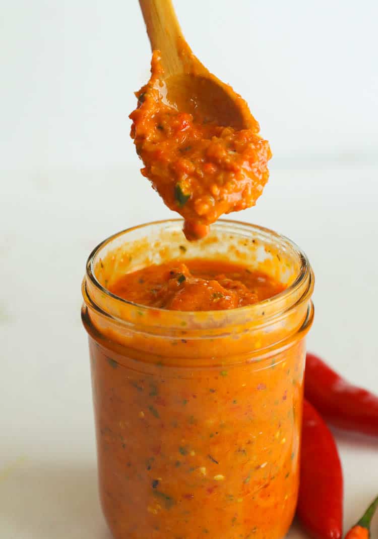Spooning up beautifully spicy Peri Peri Sauce in a Glass Jar