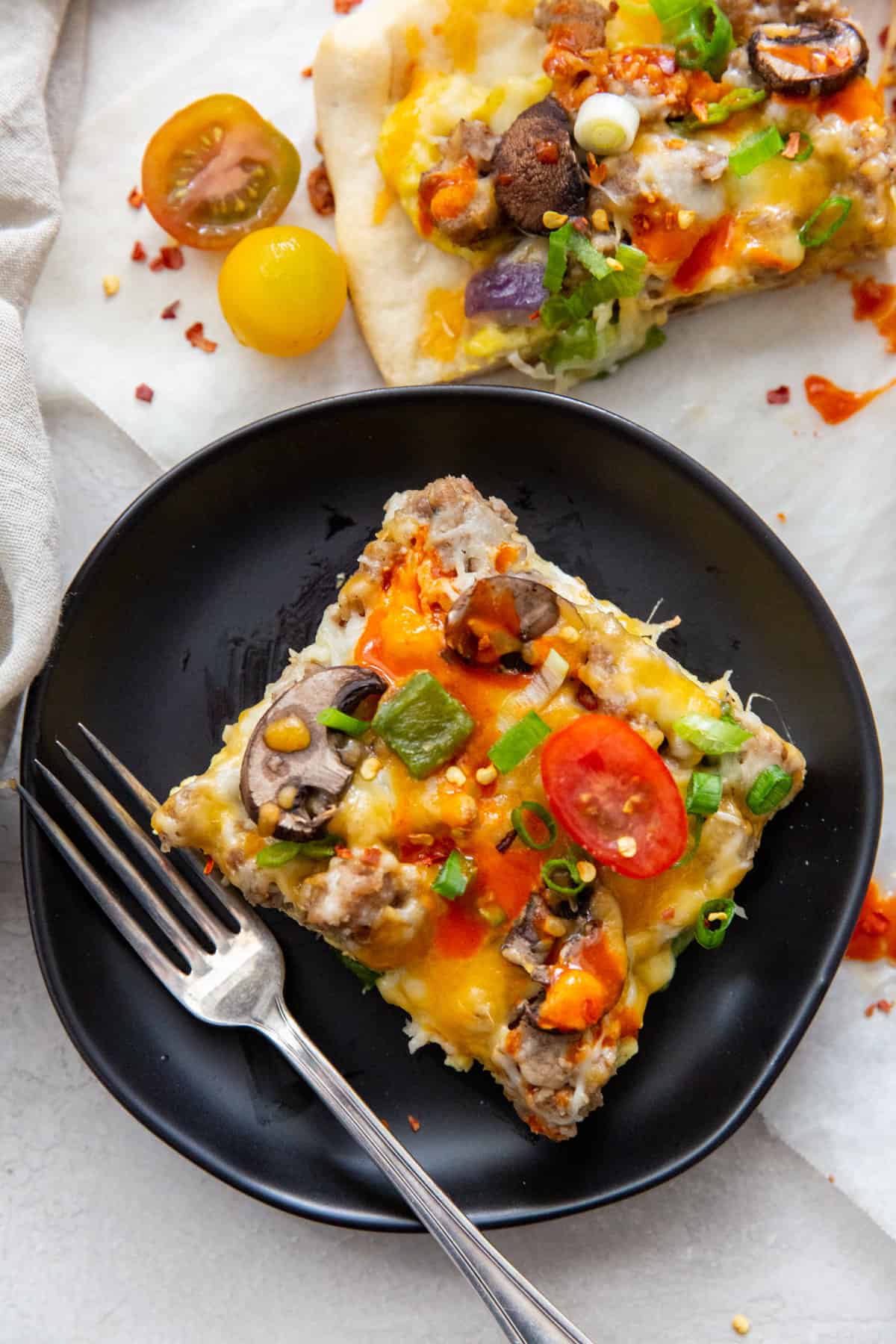 A slice of breakfast sausage pizza on a brown plate