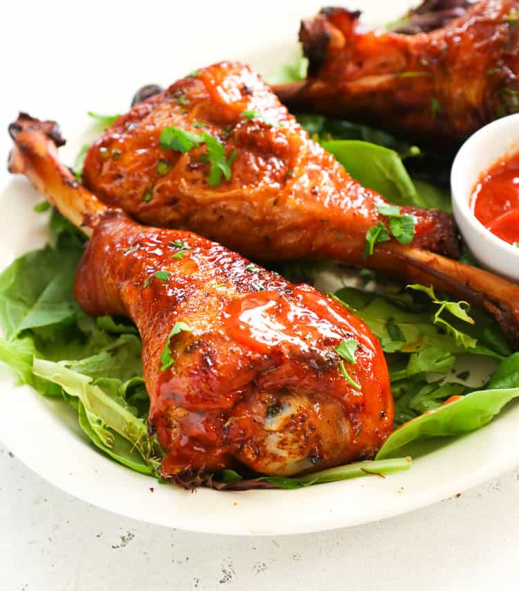 smoked turkey legs garnished over greens with sauce