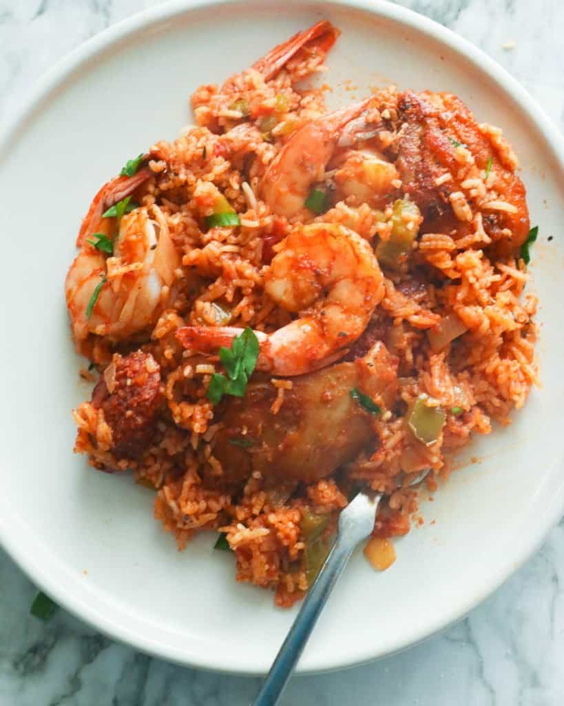 A plate of freshly cooked jambalaya with shrimp, sausage, and chicken and garnished with parsley.