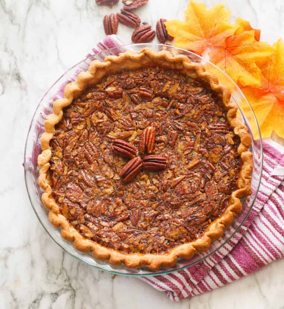 Bourbon Pecan Pie with Pecans and Fall Leaves in the Background