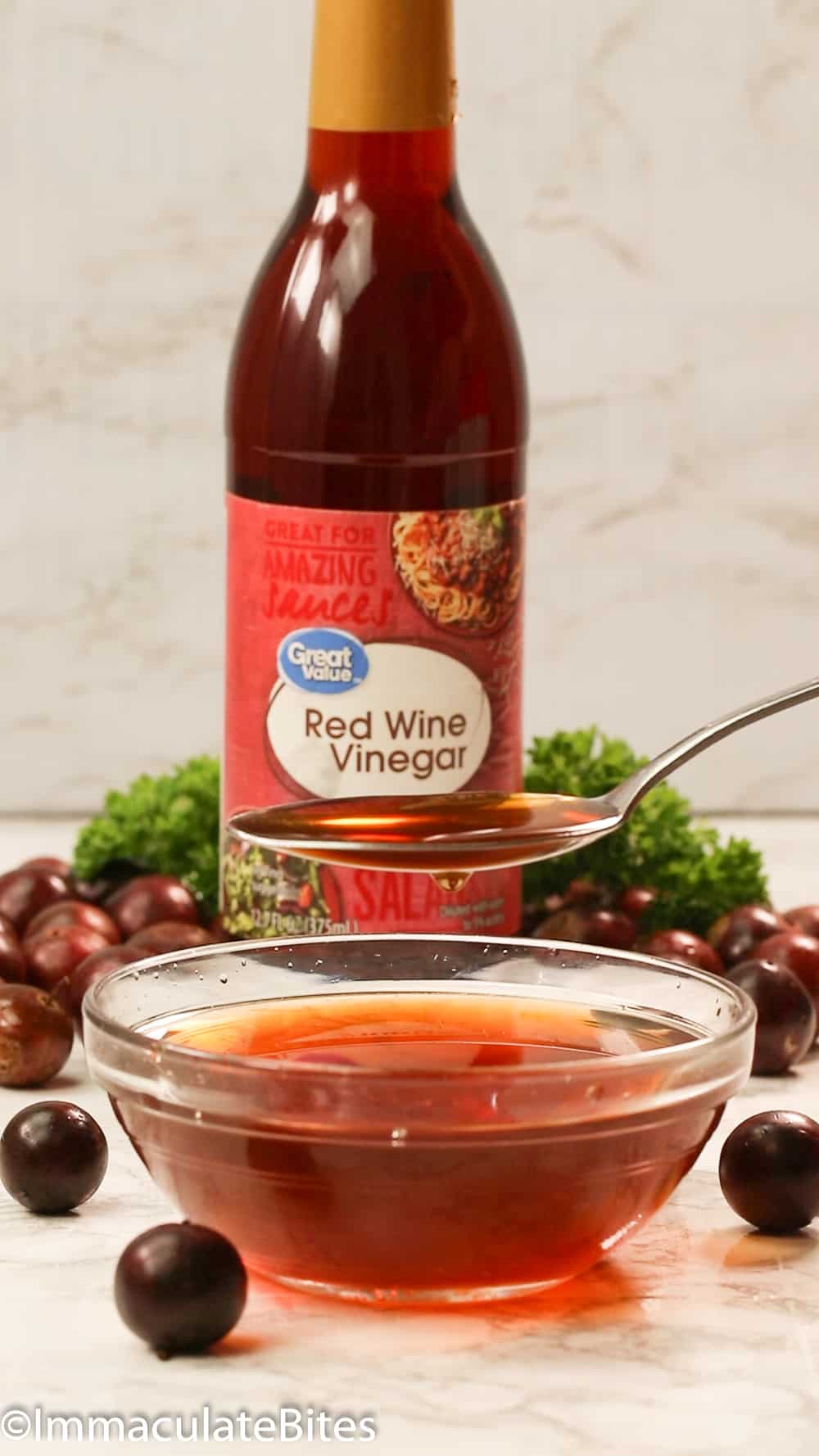 A bottle of red wine vinegar with some in a bowl ready to make a marinade.