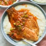 Fried fish with sauce on a bowl of grits