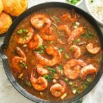 Shrimp gumbo in a black saucepan with cornbread on the side