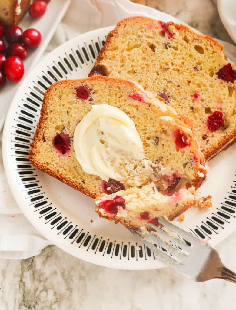 Slices of Cranberry Orange Bread Smothered with Butter