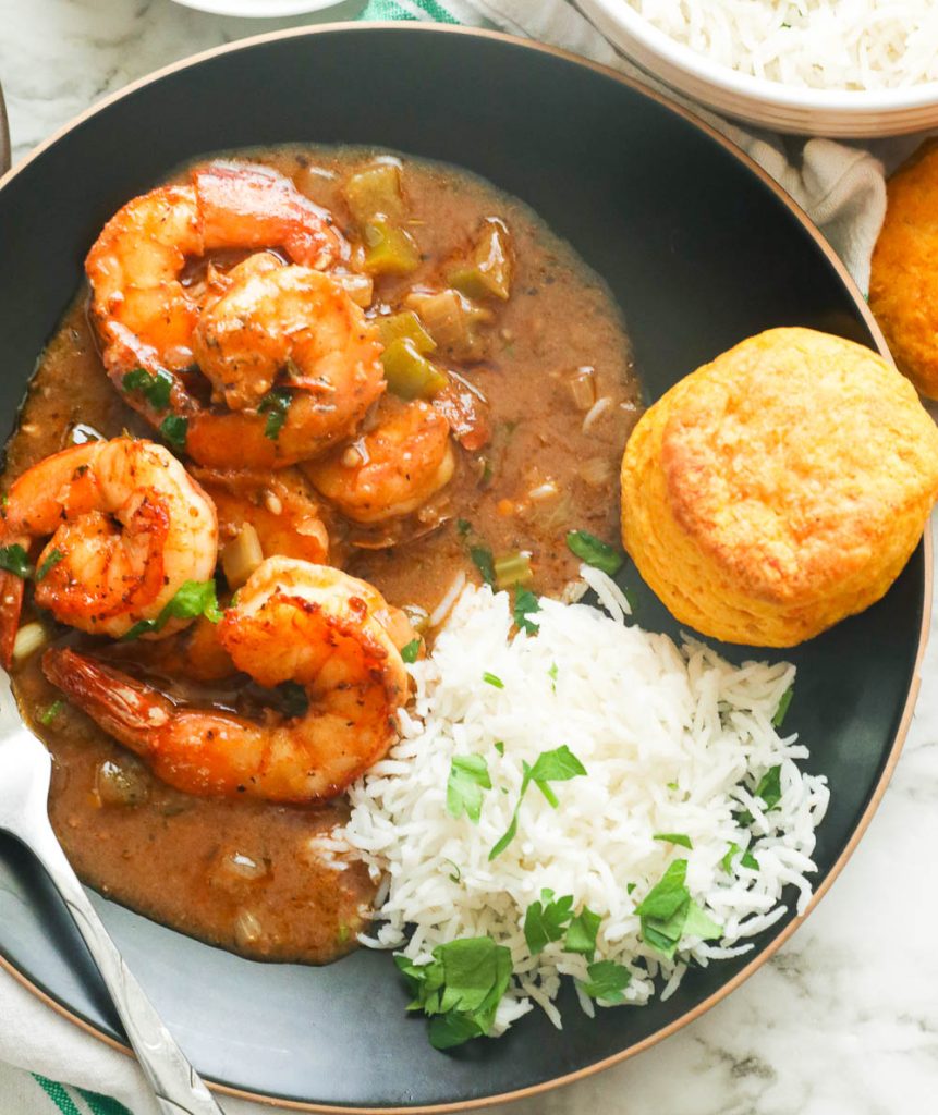 Shrimp gumbo with rice and biscuit on a plate