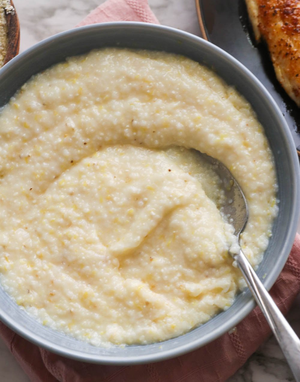a gray bowl of grits swirled with a spoon