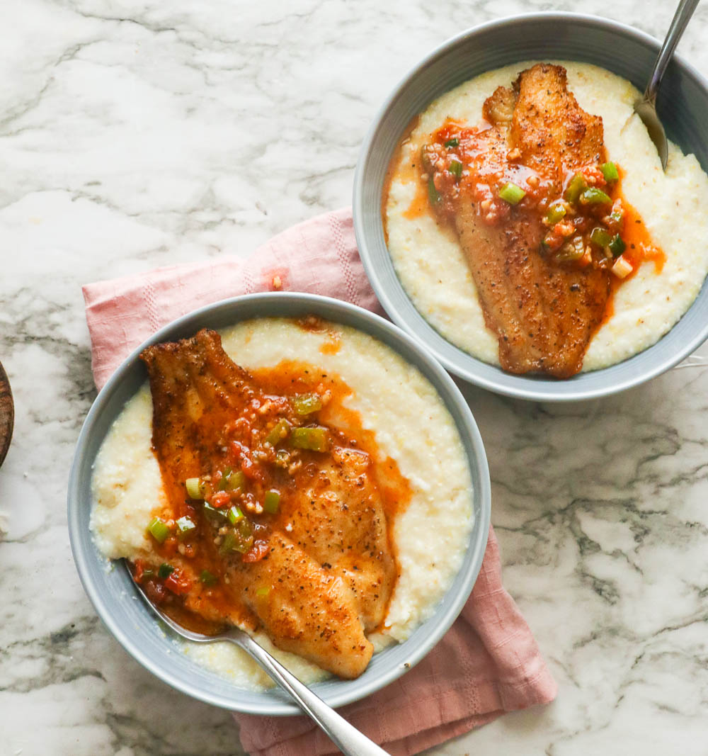 two bowls of stone-ground grits topped with pan-fried fish and sauce