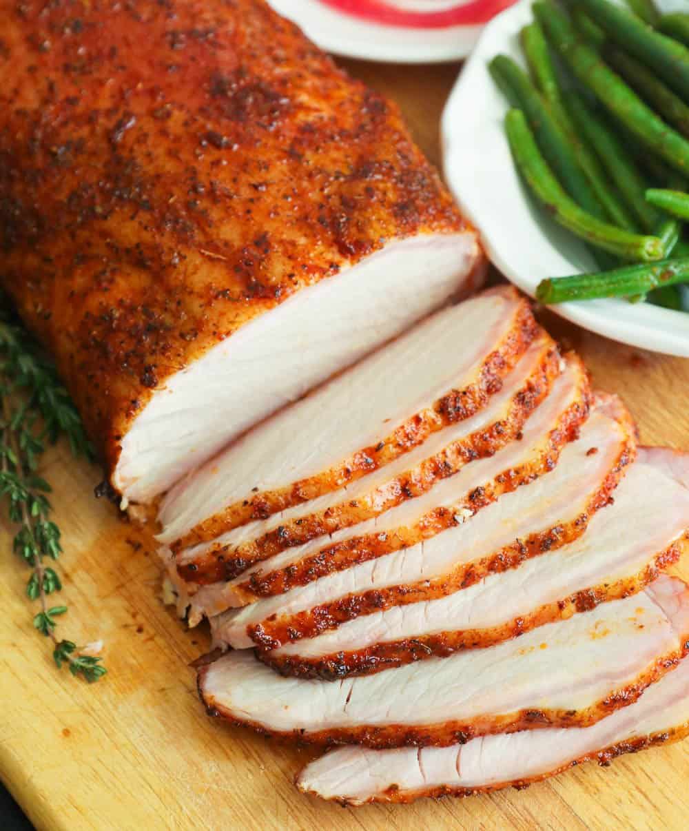 Smoked pork loin close-up with green beans and tomatoes