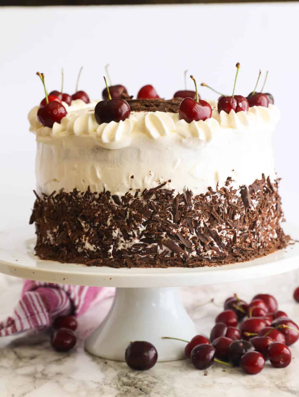 Black Forest Cake on a Cake Stand with Some Cherries in the Background