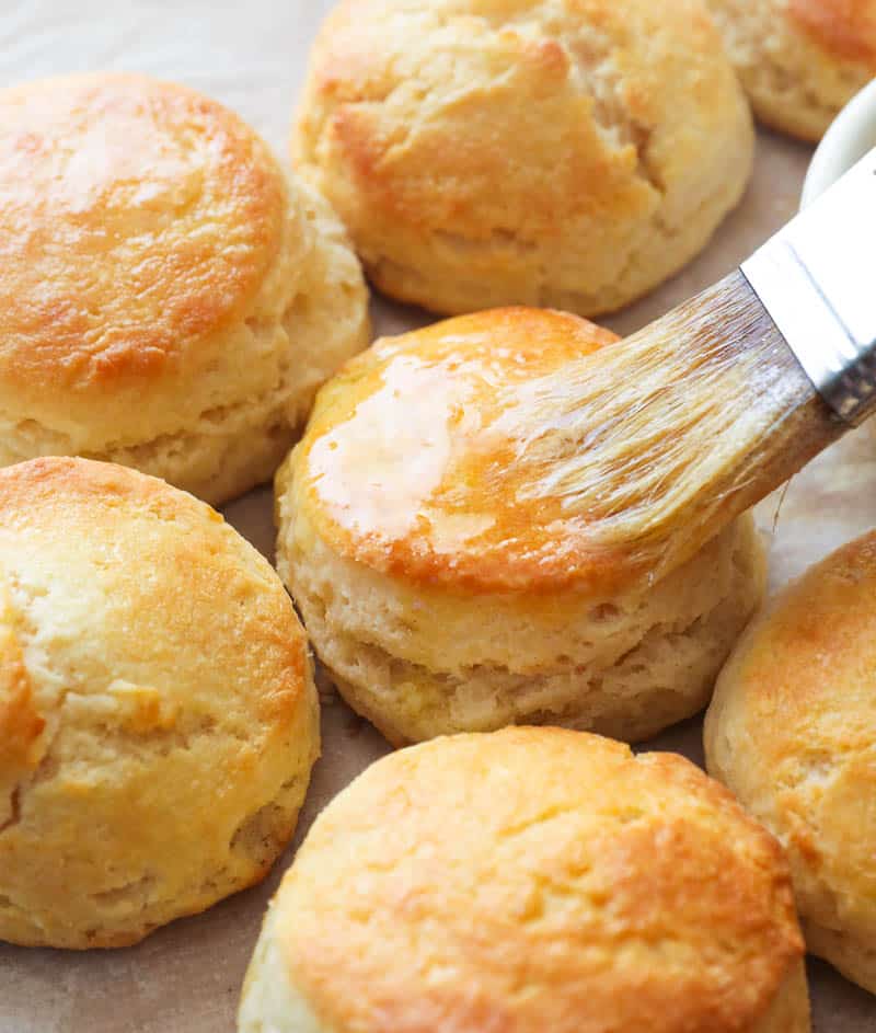 Brushing melted butter on homemade biscuits
