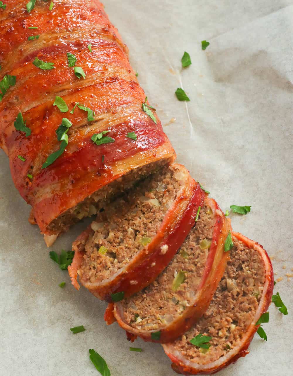 Homemade bacon-wrapped meatloaf garnished with fresh chopped parsley