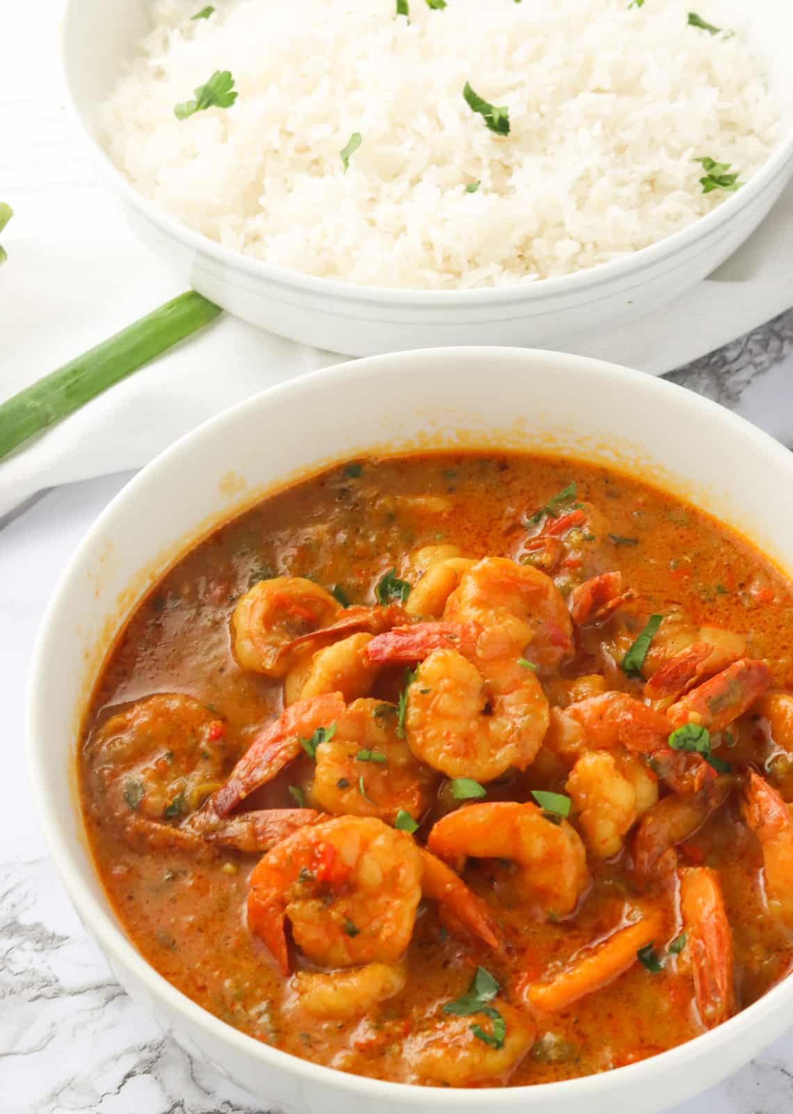 A Bowl of Jamaican Curry Shrimp with a Bowl of Rice in the Background
