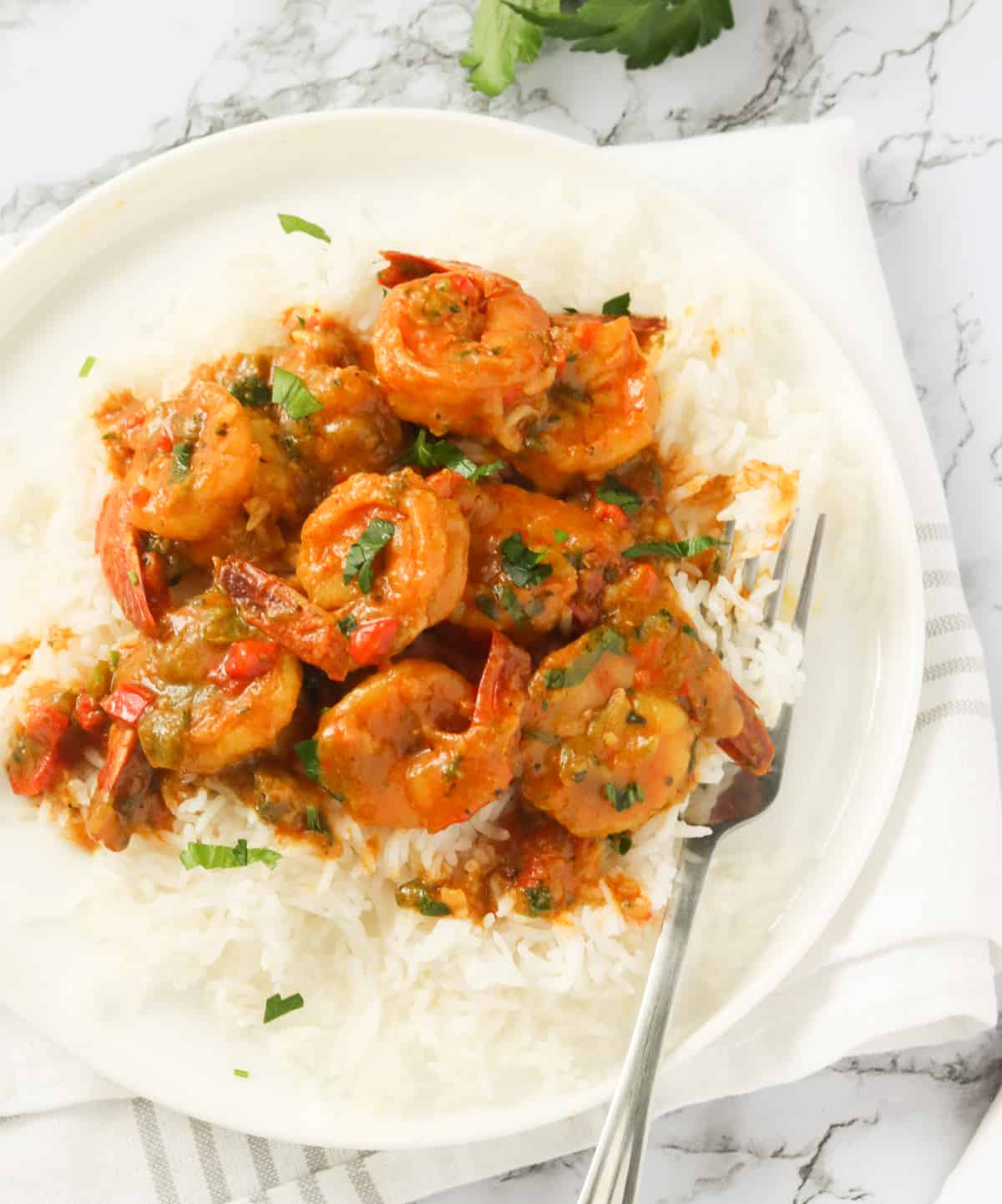 A plate of white rice topped with Jamaican curry shrimp