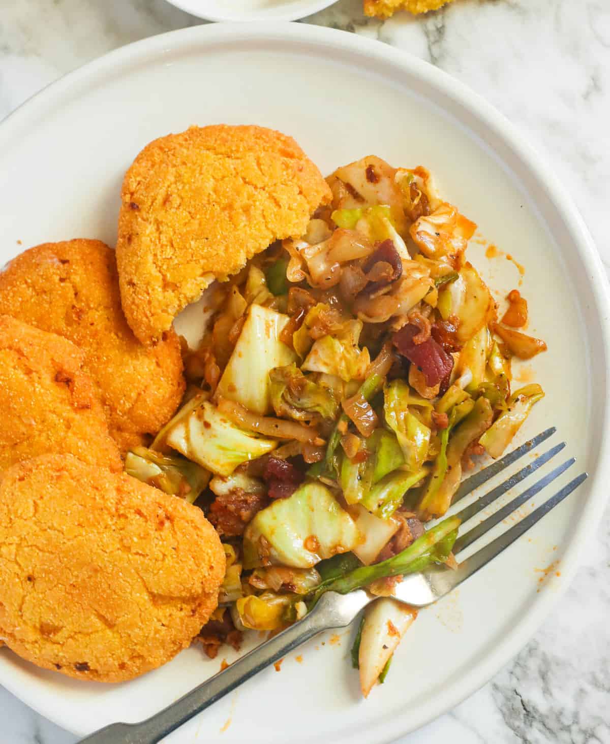 a plate of hot water cornbread served with fried cabbage