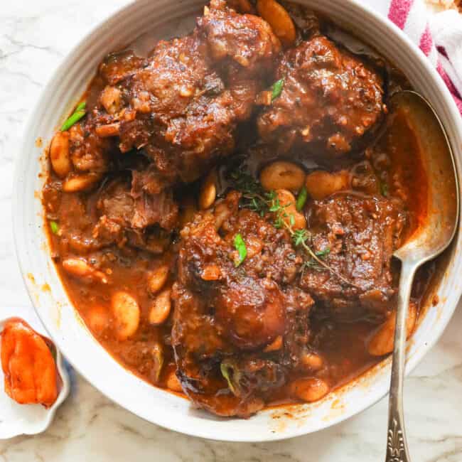 a bowl of Jamaican oxtail stew with a Scotch bonnet on the side