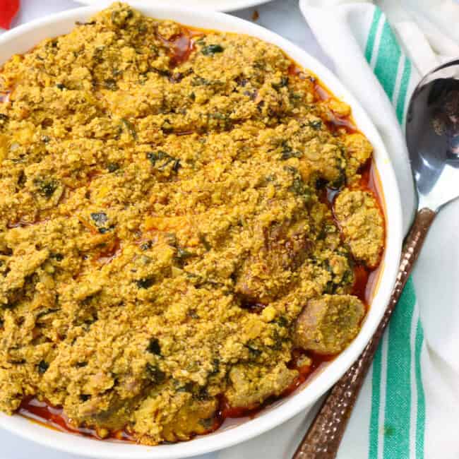 a bowl of egusi soup with plantains in the background