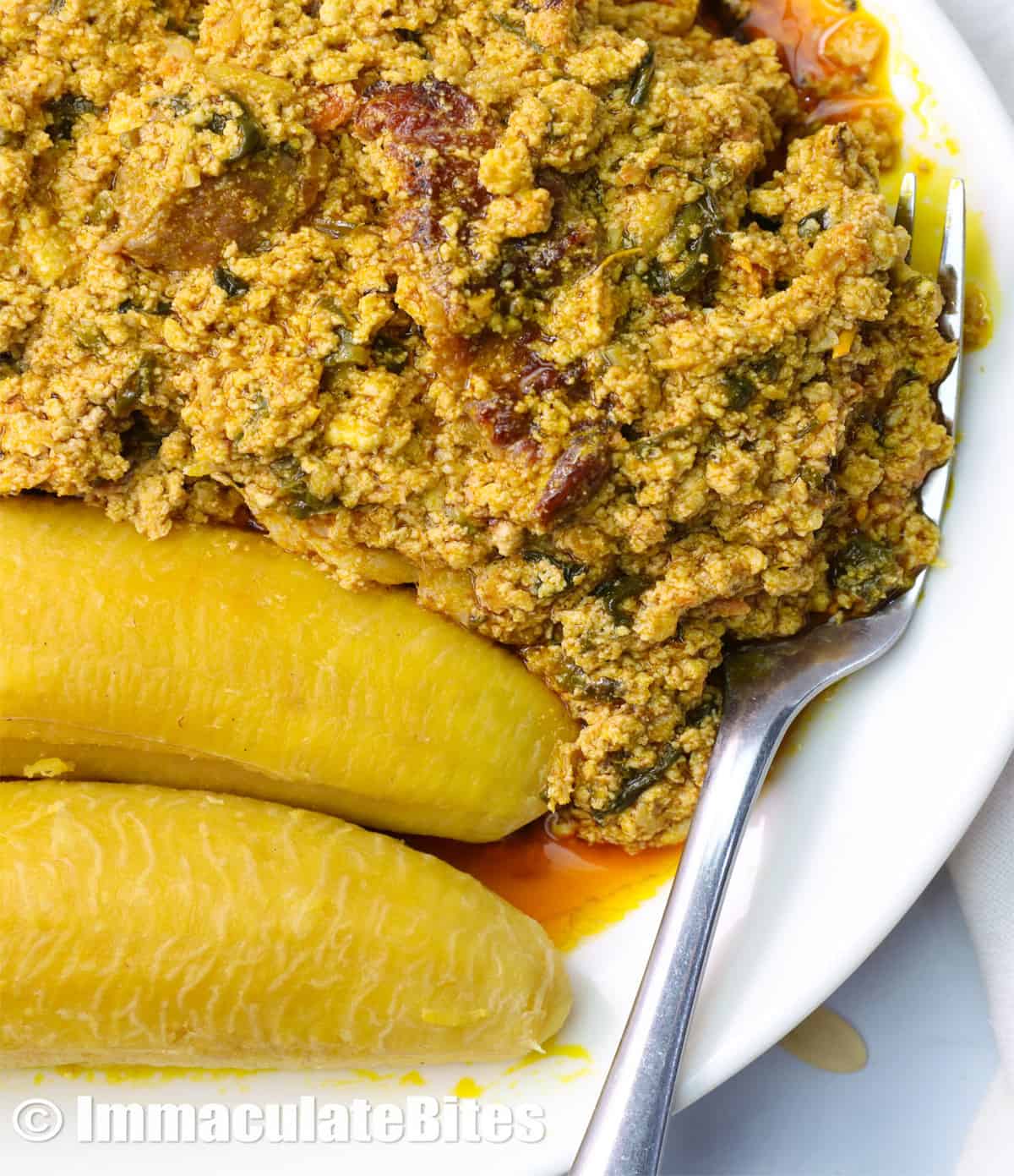a plate of egusi soup served with two plantains
