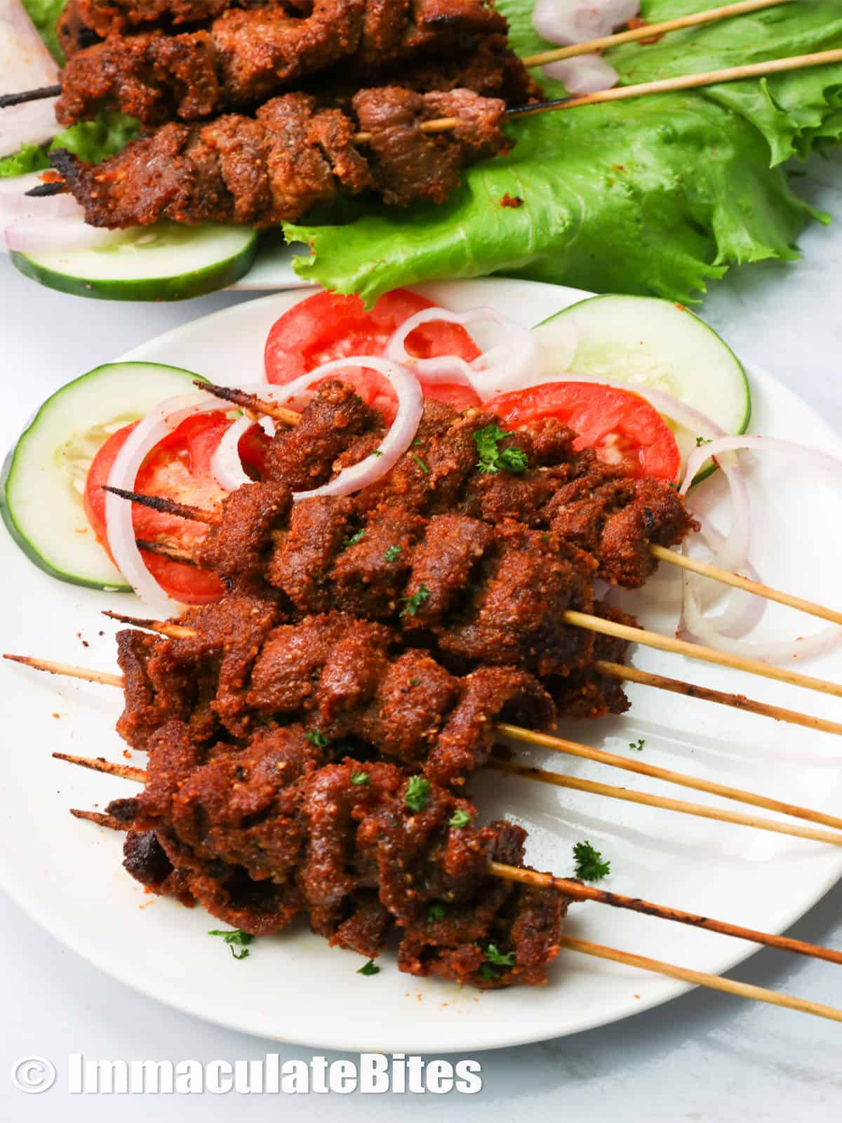 plated suya beef with cucumber and tomato slices