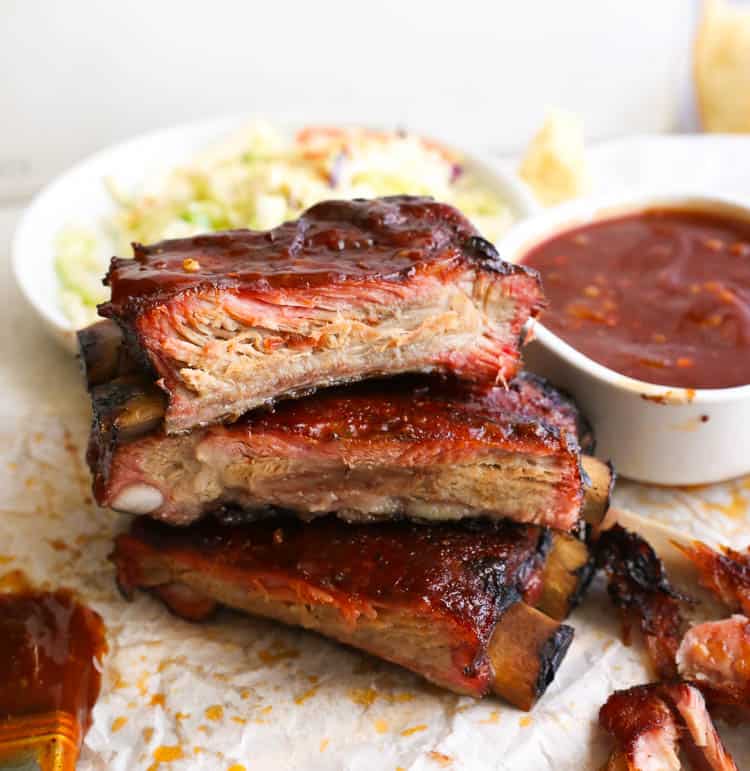 3-2-1 Smoked ribs stacked with BBQ sauce and coleslaw in the background