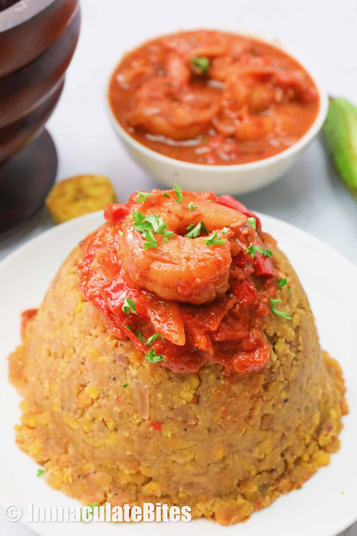 Mofongo mound topped with shrimp sauce and more shrimp sauce in the background