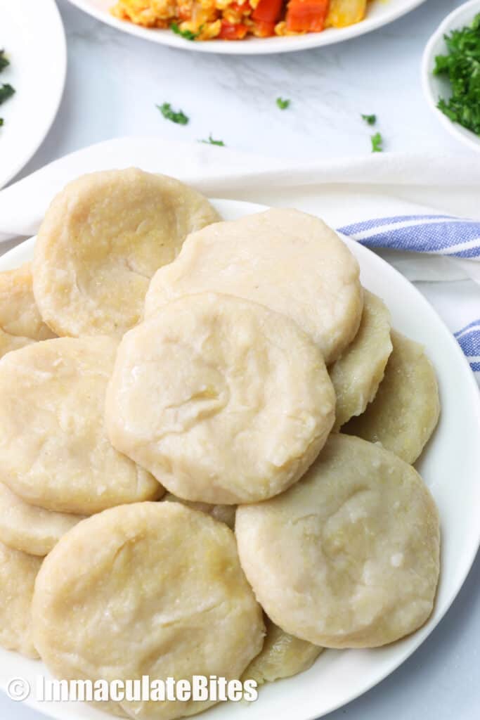 A plateful of Caribbiean Boiled dumplings with ackee and saltfish in the background