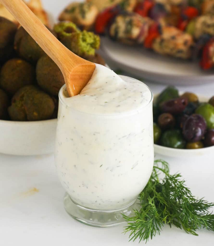 Dill sauce in a glass with a wooden spoon