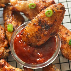 Dipping crispy grilled chicken wings in red sauce