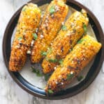 A plateful of grilled corn sprinkles with cilantro and queso fresco