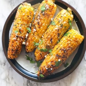 A plateful of grilled corn sprinkles with cilantro and queso fresco